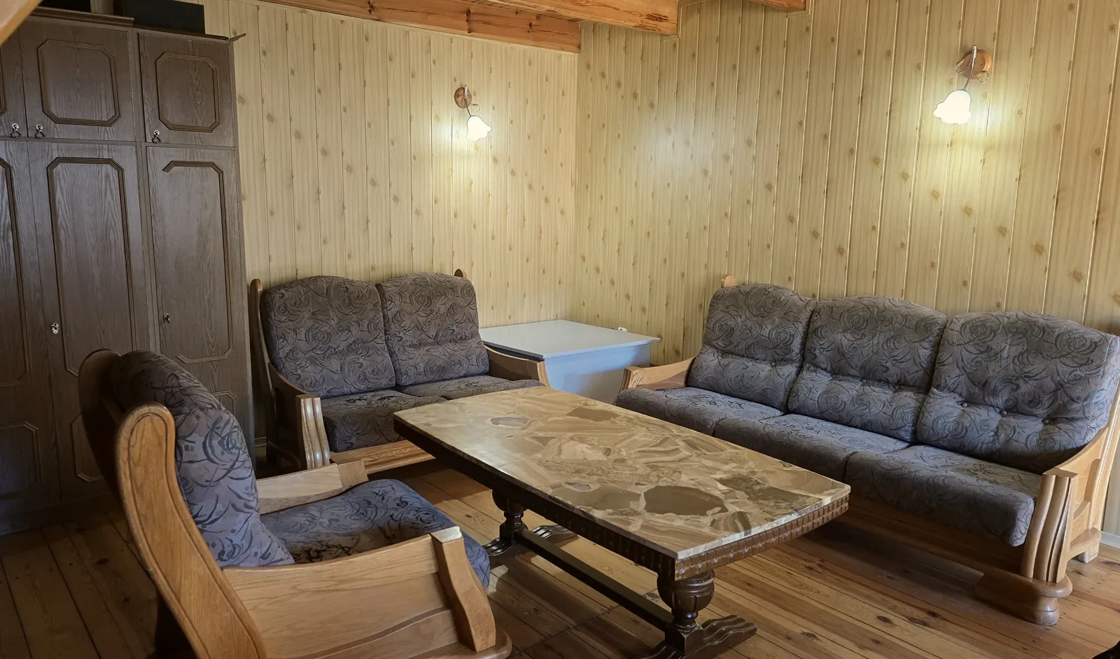 Domek 1 w ośrodku Ambrowil w Lidzbarku Welskim – salon z sofami, stolikiem kawowym i drewnianym wykończeniem