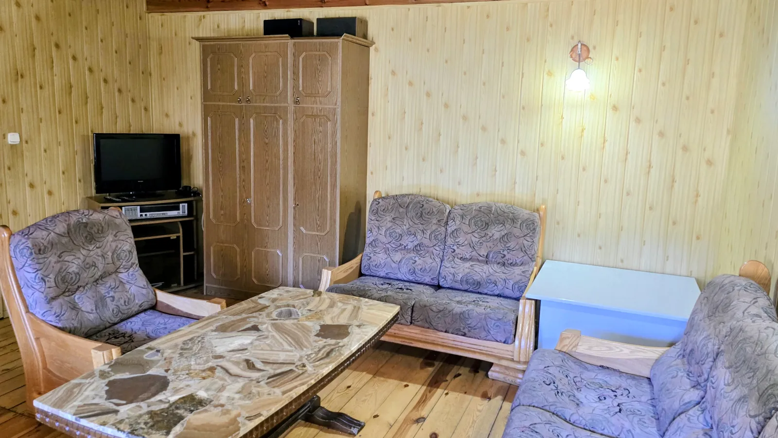 Domek 1 w ośrodku Ambrowil w Lidzbarku Welskim – salon z telewizorem, stolikiem i miejscem do wypoczynku